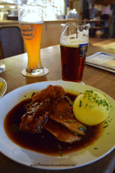 Geroosterd varkensvlees met krokant vel in donkere biersaus en dumplings bij Augustiner in München.